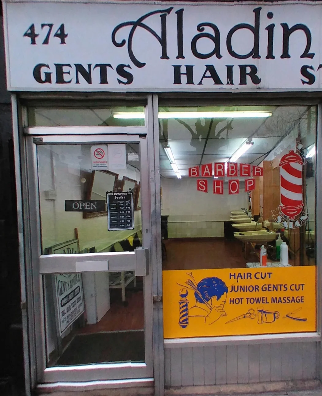 Aladin at 474 Kingsland Road: the hand-painted style fascia lettering, glass door with OPEN sign, BARBER SHOP window letters, pole decal and orange panel listing hair cut, junior gents cut and hot towel massage