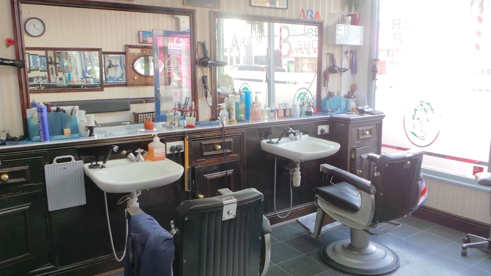 Inside Ara's Barber Shop: dark-wood counters with white ceramic sinks, large mirrors and vintage barber chairs