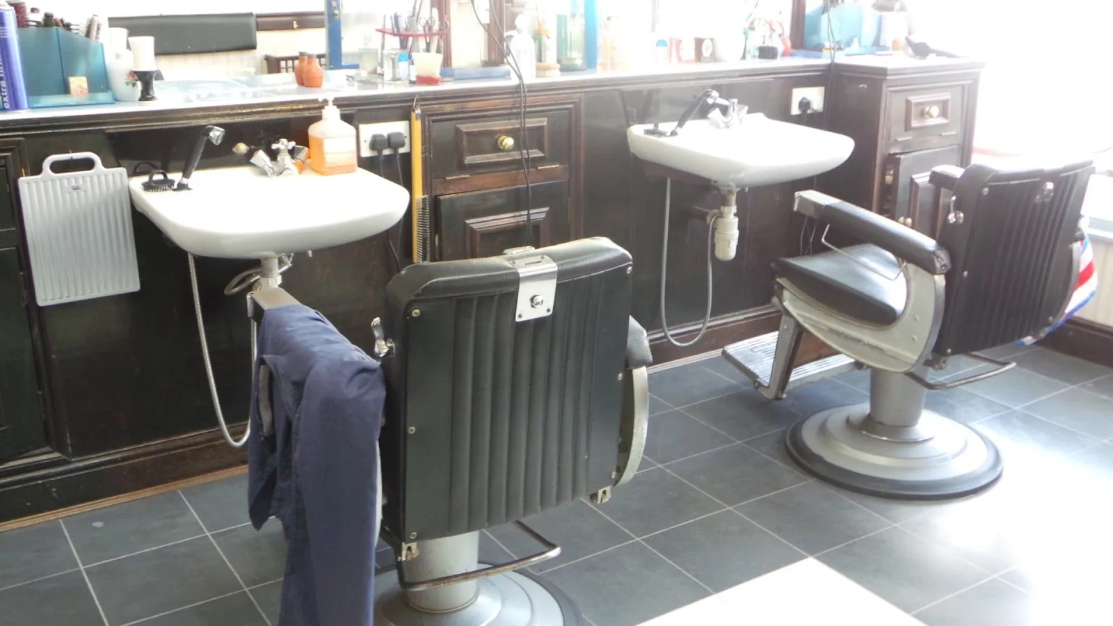 Two vintage barber chairs and white sinks at Ara's Barber Shop