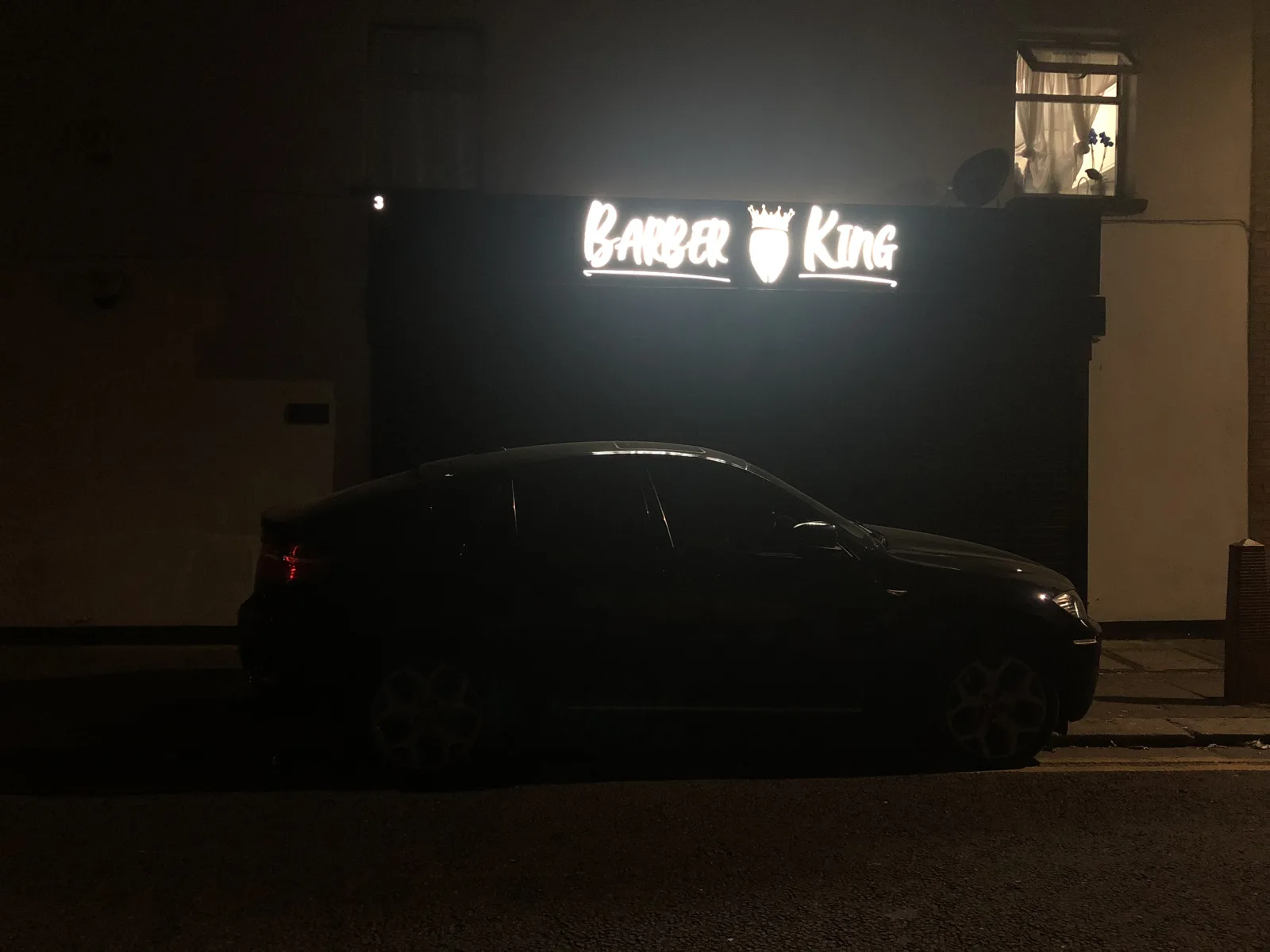 Barber King at night: the illuminated 'Barber King' script sign with its crown logo glowing above the Balmoral Road shopfront