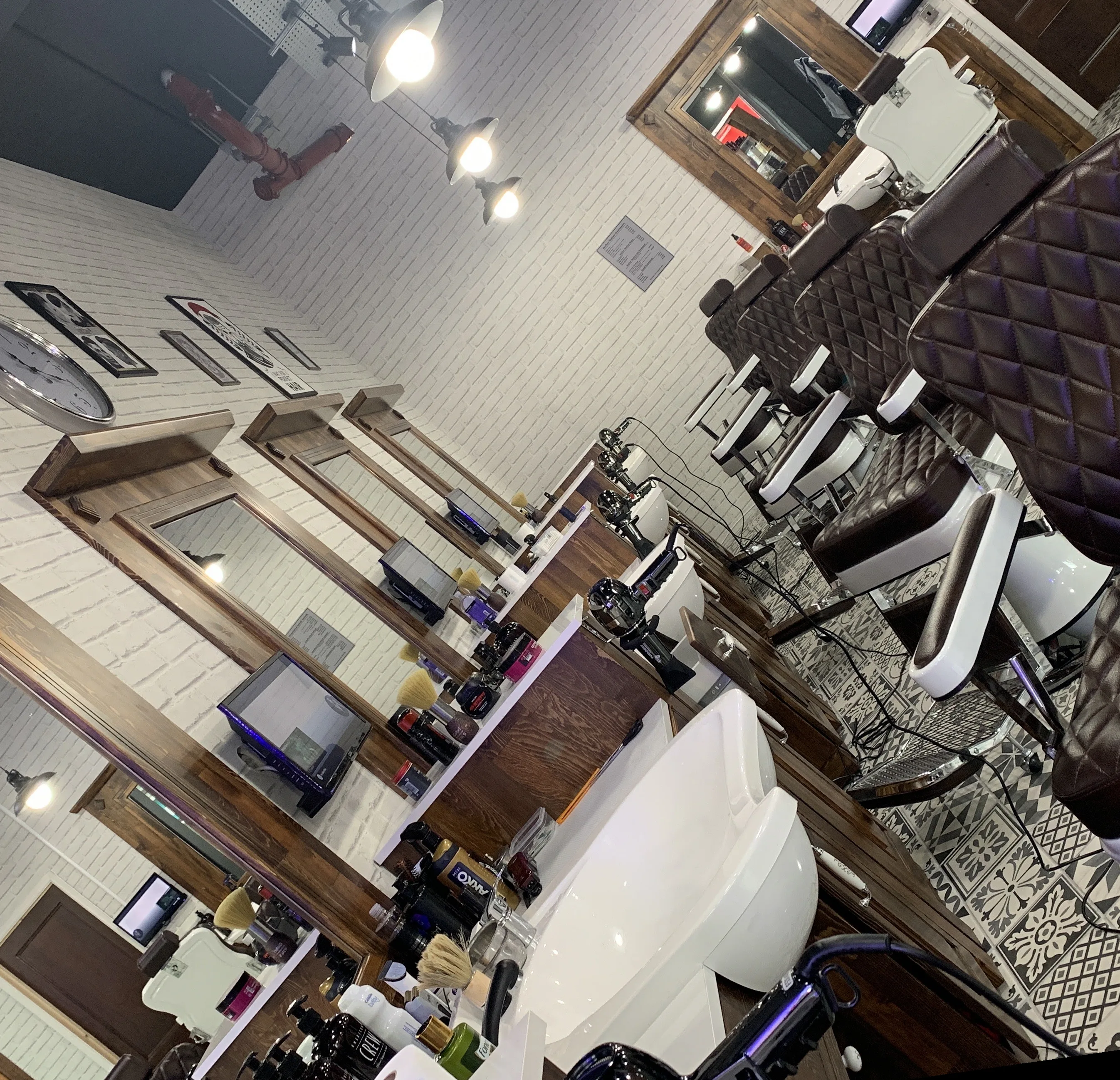 Inside Barber Station: quilted brown leather barber chairs, white ceramic sinks, wood-framed mirrors and white brick walls
