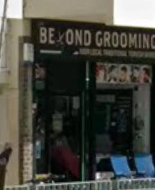 Beyond Grooming's shopfront on the pedestrian square off Haggerston Road, its black fascia sign above the window with blue chairs visible inside
