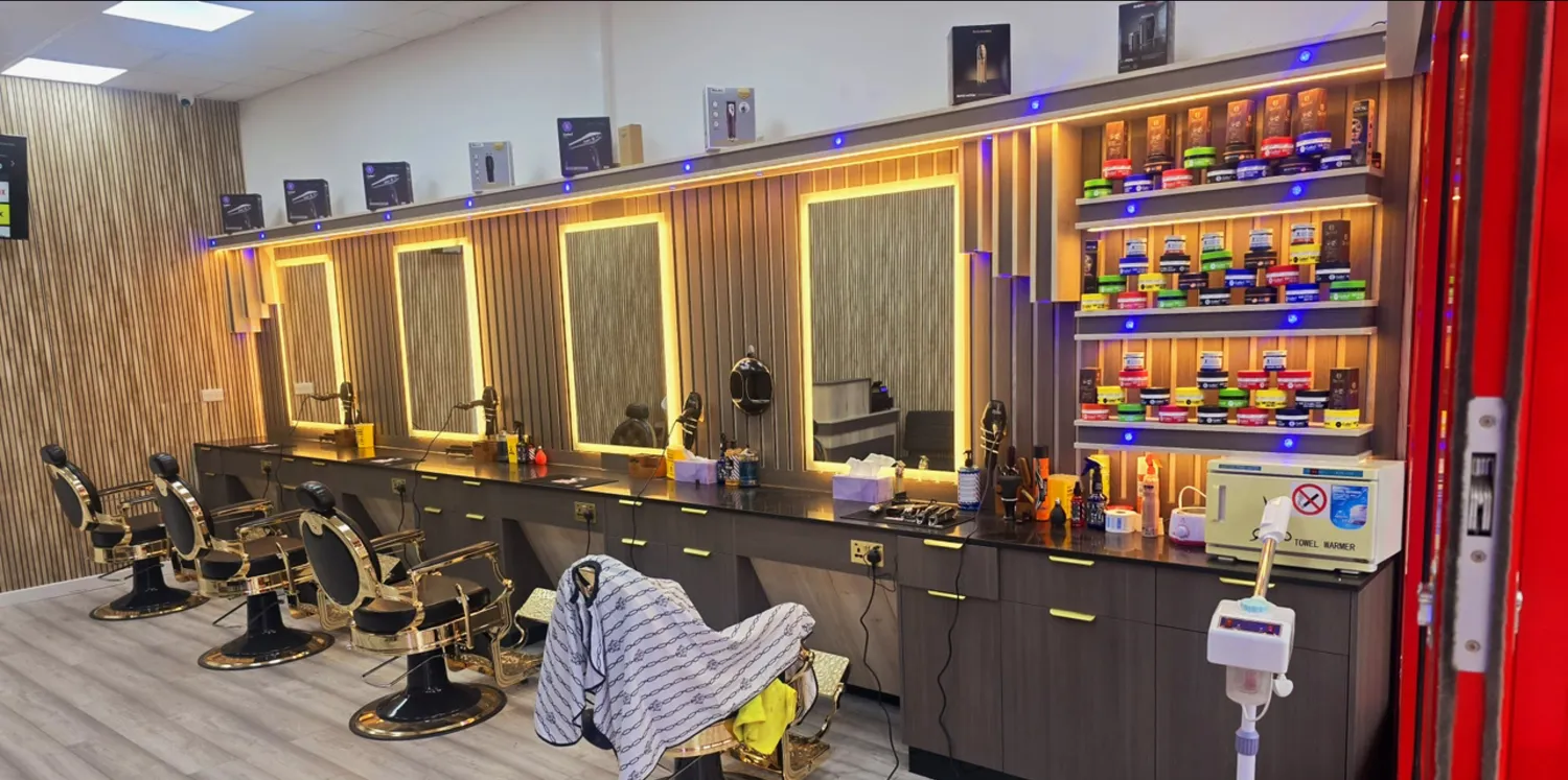 Inside City Barber Mo — long room with backlit mirrors and wood-slat walls