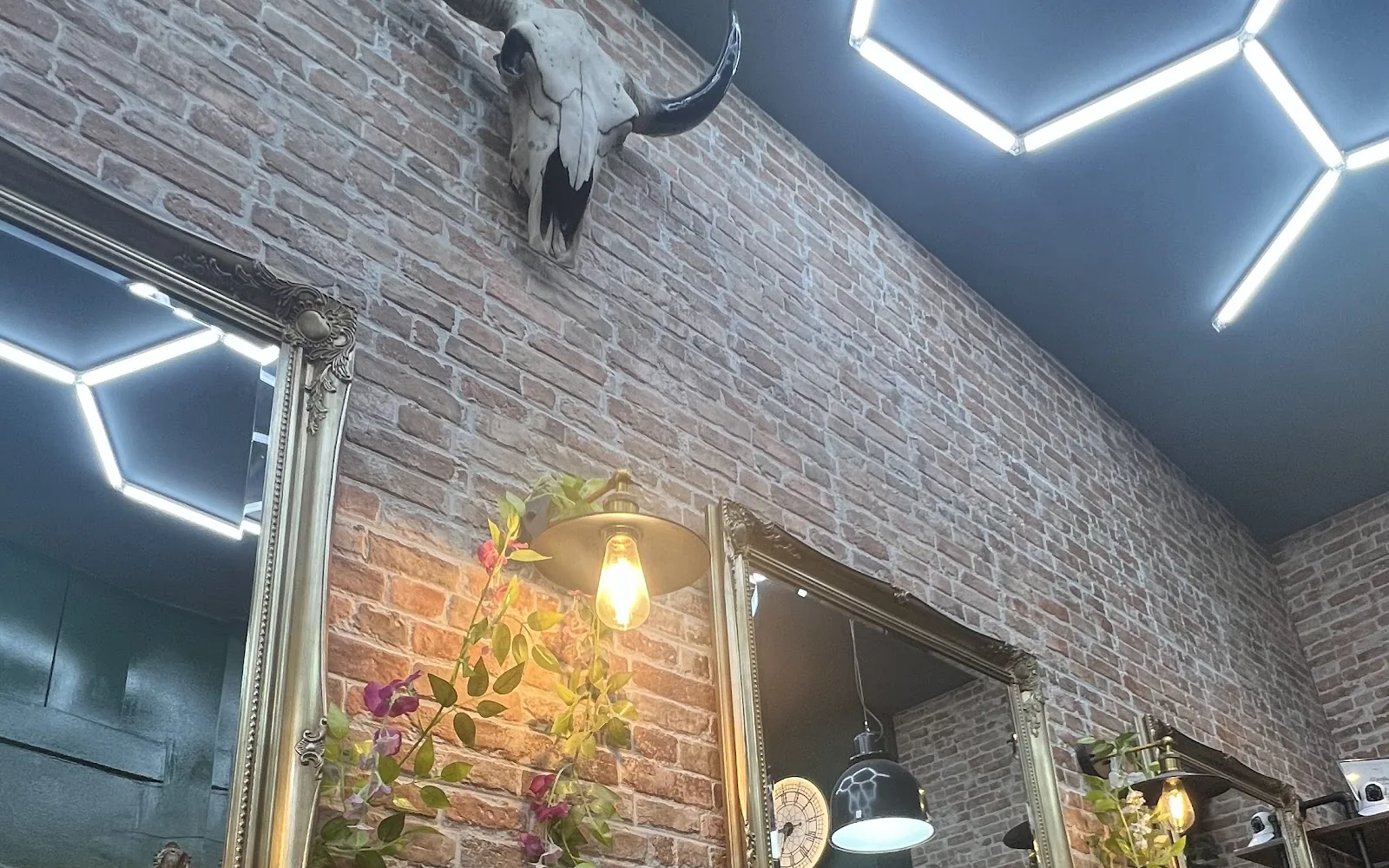 A workstation at Cut & Go: brass-framed mirrors, a longhorn skull on the brick wall and barber tools on the counter