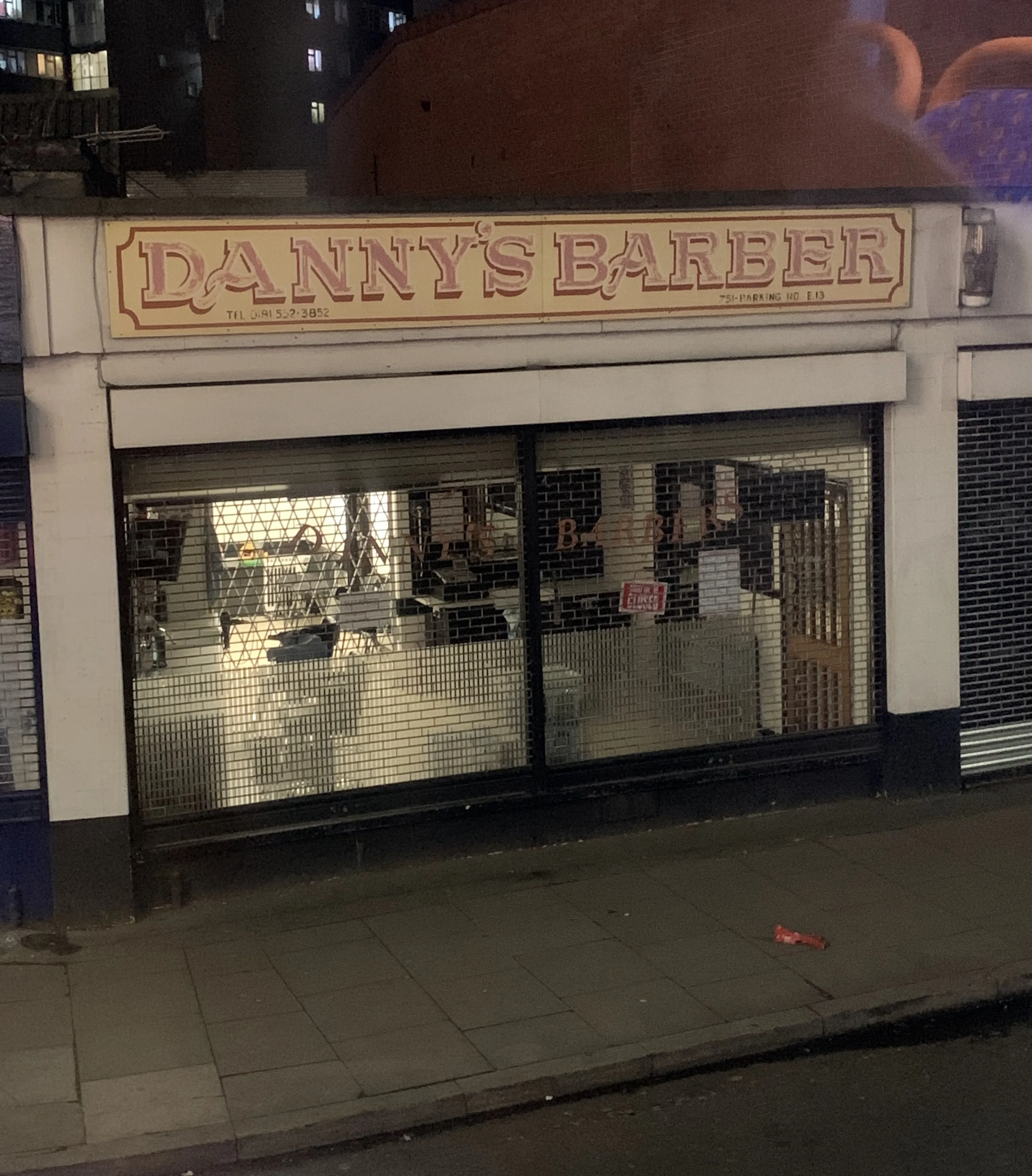 Danny's Barber at night: the vintage red-lettered fascia above the shuttered glass frontage on Barking Road