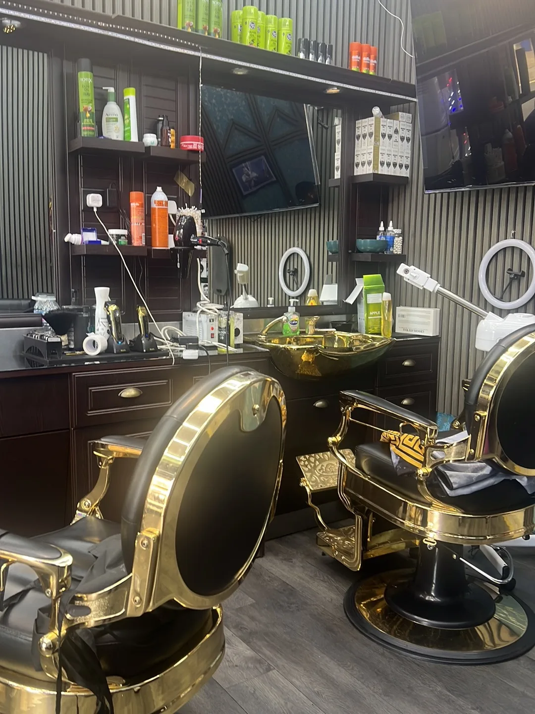 Inside Gentleman Barbers: ornate gold barber chairs, a gold sink basin, dark wood units and product shelves