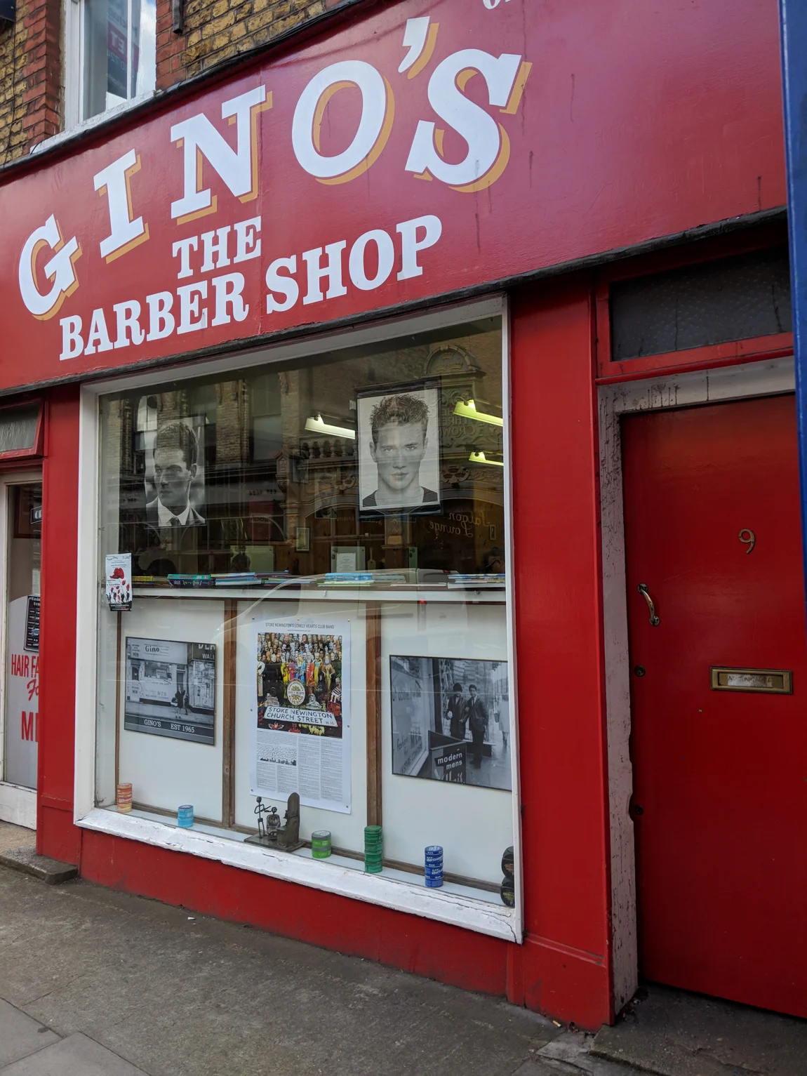 Gino's on Church Street: the bright red fascia with GINO'S THE BARBER SHOP in white letters, the window posters and framed 1965 photo, product tins on the sill and the red door of number 9