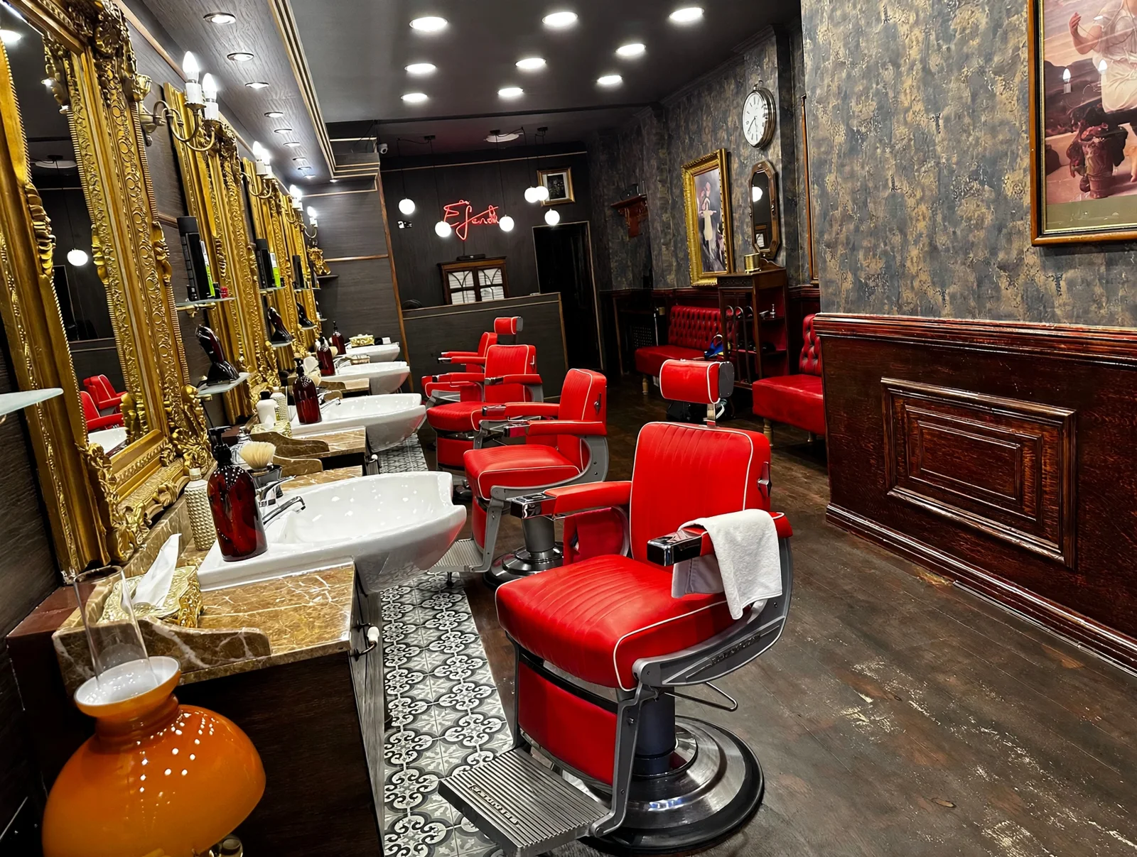 Inside Golden Scissors: ornate gold-framed mirrors, white sinks, scarlet barber chairs, dark mottled wallpaper and patterned floor tiles
