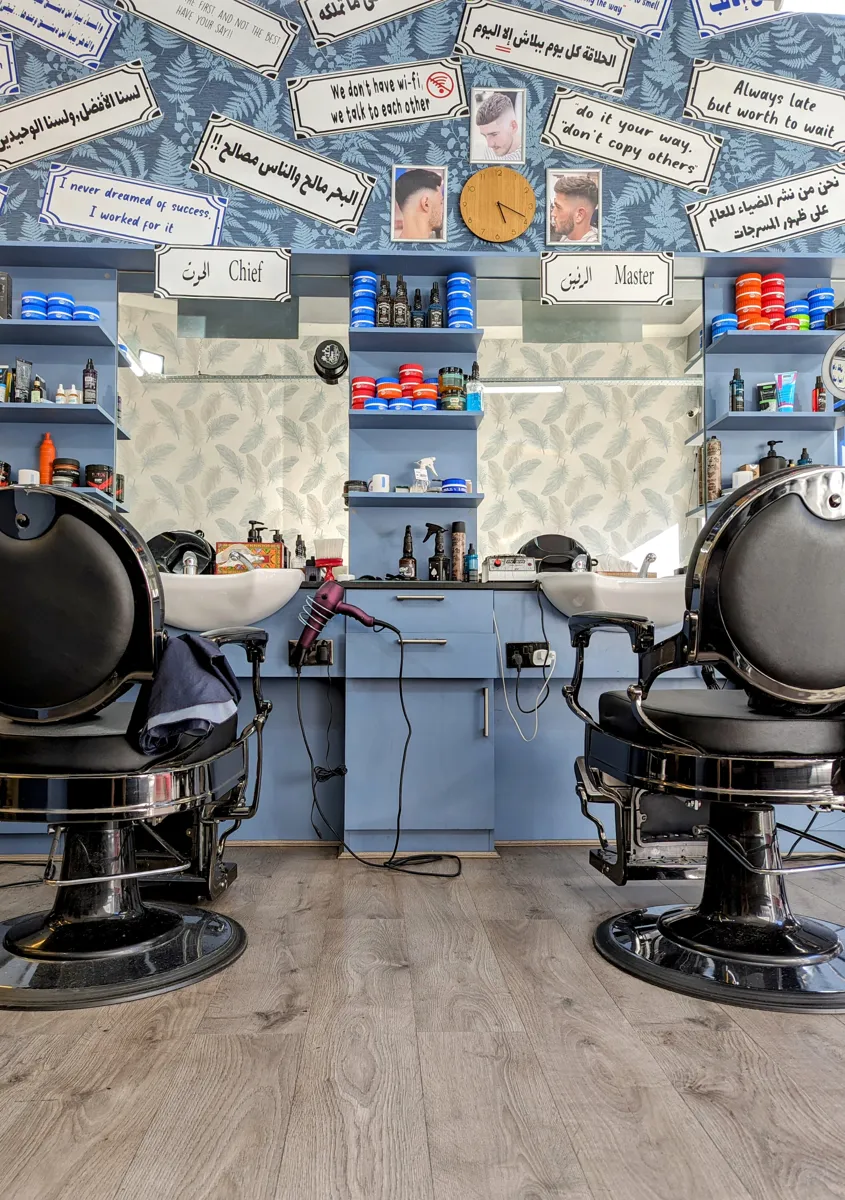 Inside Horn Lane Barbers — chrome chairs, blue cabinets and the wall of motto signs