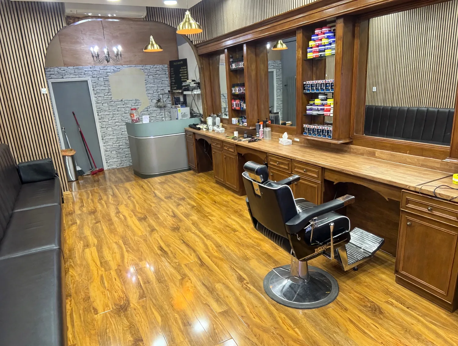 Inside KING'S BARBERS: polished wooden floor, a black barber chair, the long timber mirror counter with product shelves and a stone feature wall