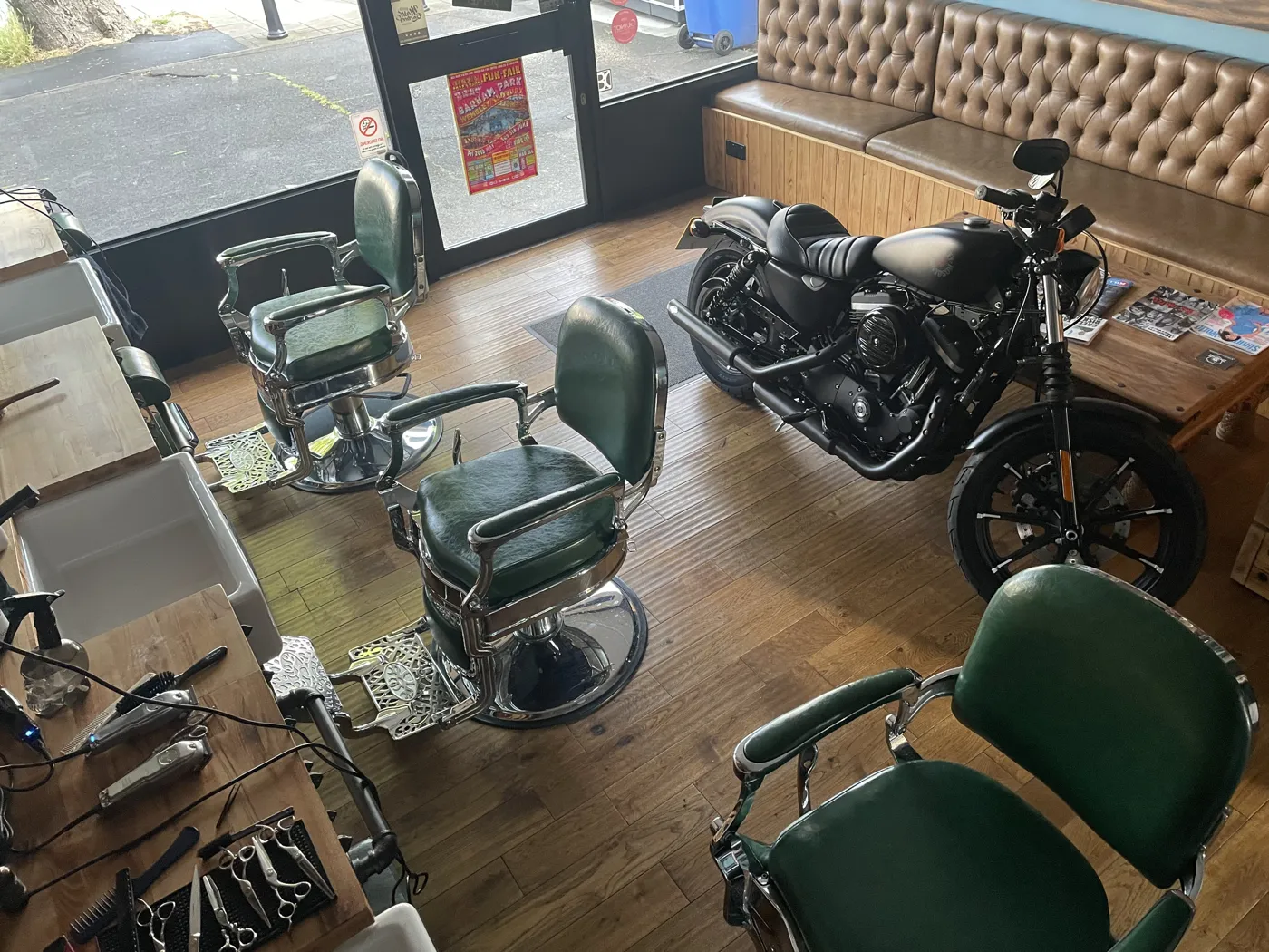 Inside Knights of London — green leather barber chairs, wooden floor and a motorcycle parked in the shop