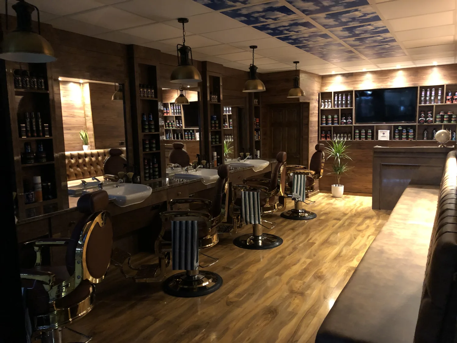 Inside Matins Barbers: walnut panelling, brass pendant lights, tan chesterfield barber chairs and a ceiling painted with sky and clouds