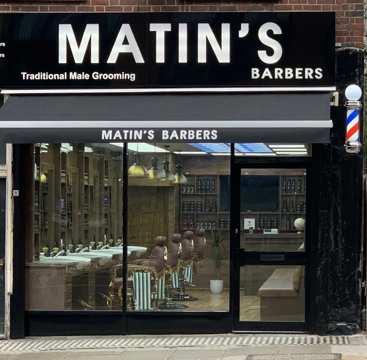 Matin's Barbers on Tooting High Street: black fascia and awning with a full glass front and barber pole