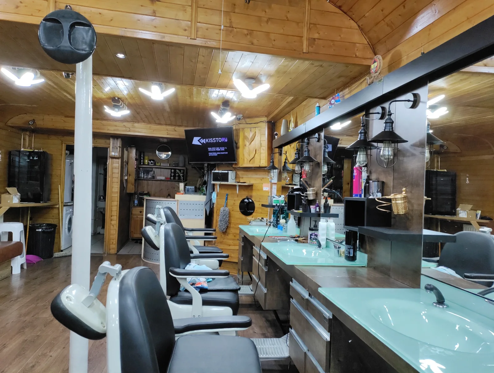 Inside MK Barbers: pine-panelled walls and ceiling, a row of black-and-white barber chairs, mint-green glass sinks, mirrors and Edison lamps