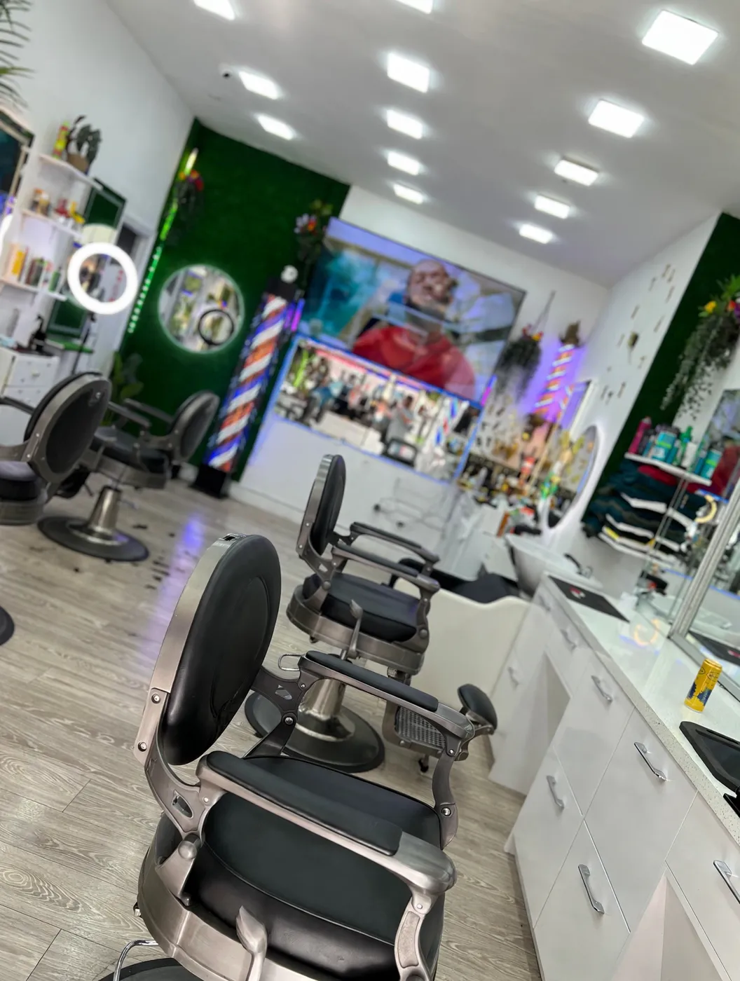 Inside MOSES FADE MASTER — green walls, barber poles and black barber chairs