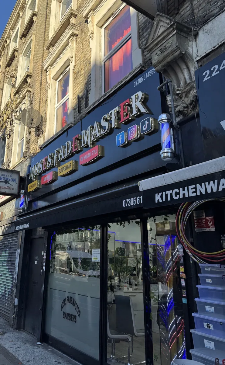 MOSES FADE MASTER shopfront with its illuminated sign on Kilburn High Road