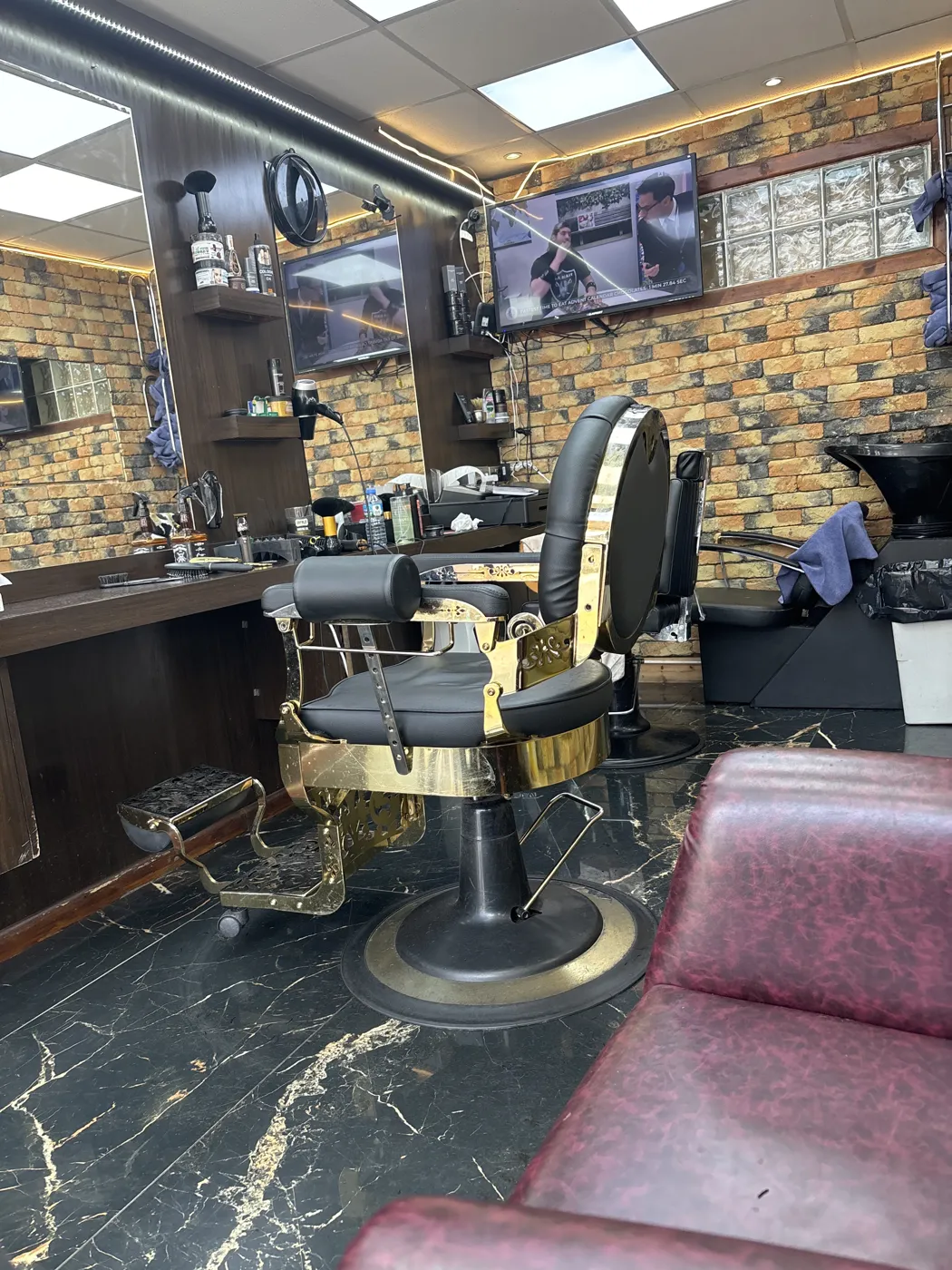 Inside MR ADAM'S BARBERS — a gold-trimmed barber chair, brick walls and marble floor