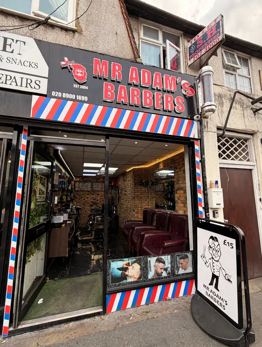 MR ADAM'S BARBERS shopfront with its red sign and barber stripes on Wembley Park Drive