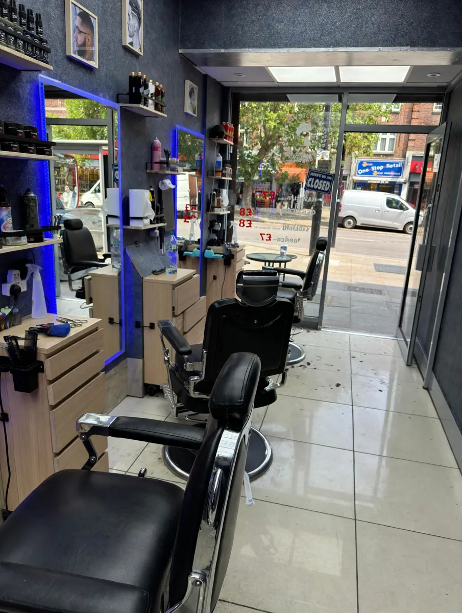 Inside Next Level Barber — dark walls, blue-lit mirrors and black chairs