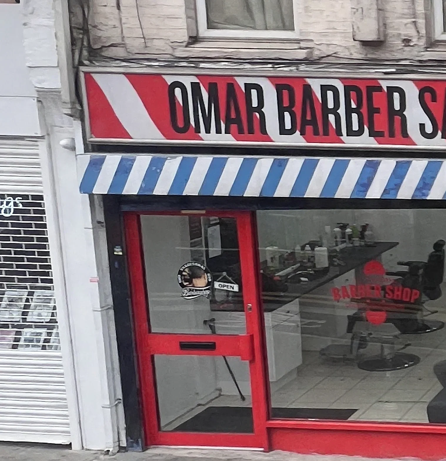 Omar Barber Salon at 16 Hoe Street: the red-and-white striped OMAR BARBER SALON fascia, blue-and-white awning, red door and window with the BARBER SHOP decal