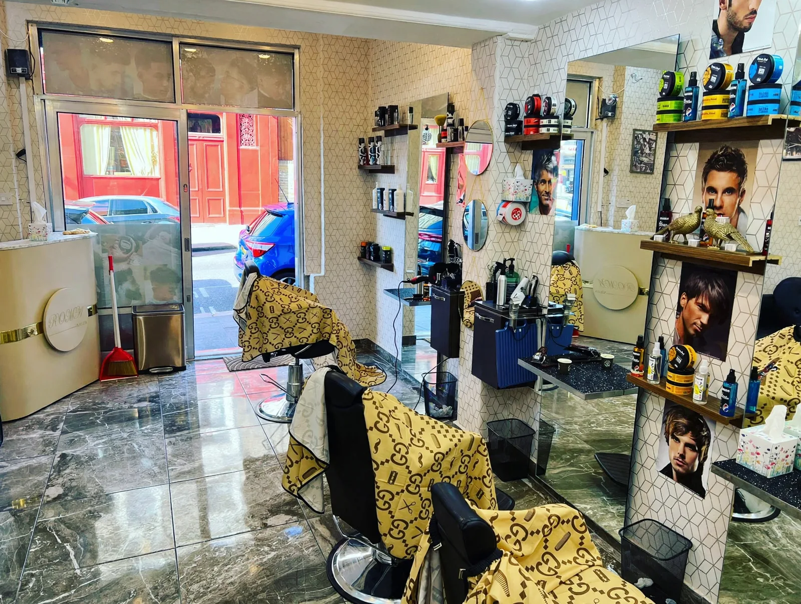 Inside Roma 1 Barber: green marble floors, barber chairs draped with gold monogram capes, mirrors and product shelves