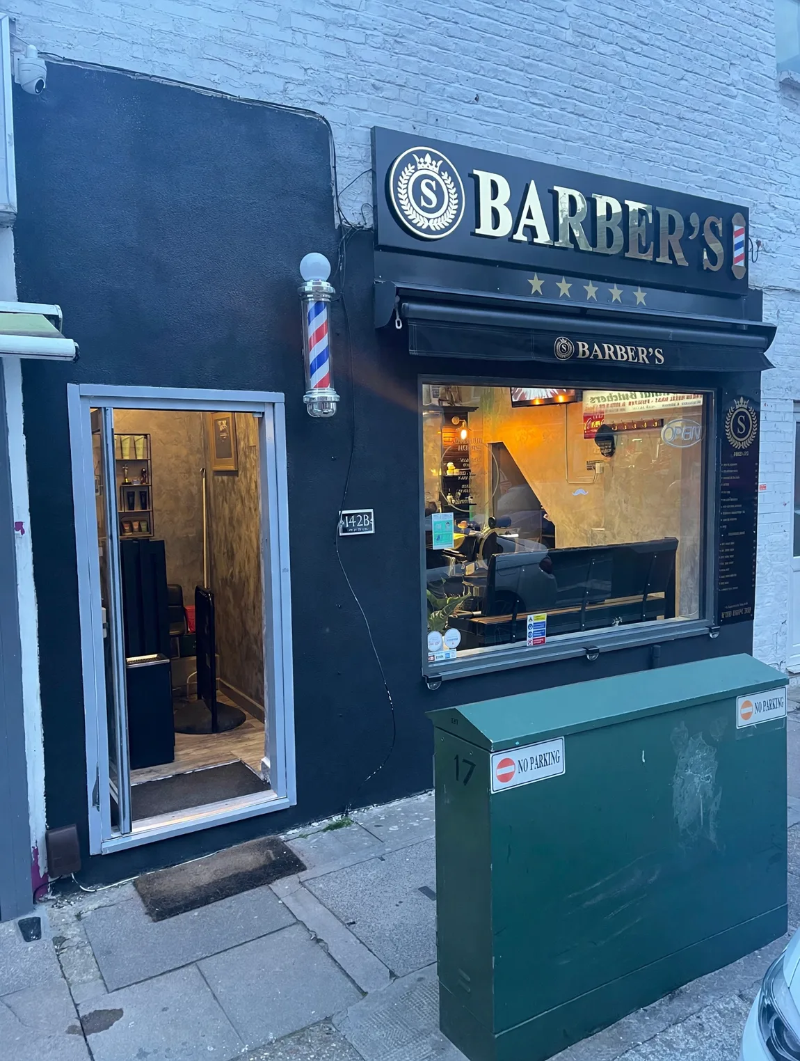 S Barber's on Willesden High Road: the black facade, gold BARBER'S sign with five stars, the barber pole and the open door at 142B