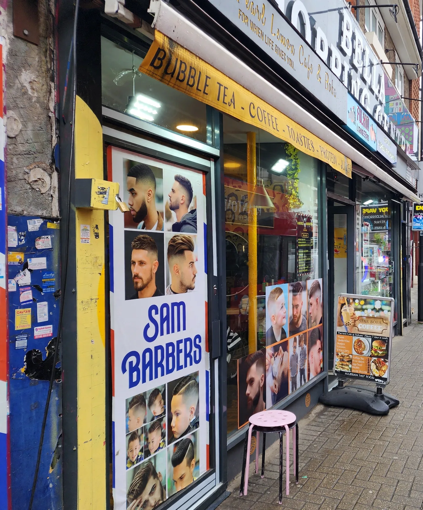 Sam Barbers on North End Road: the door and windows covered with hairstyle posters, with a pink stool outside