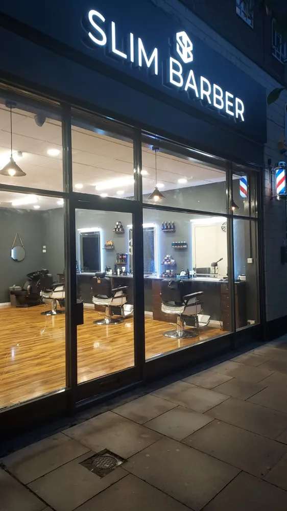 Slim Barber shopfront at night, sign illuminated
