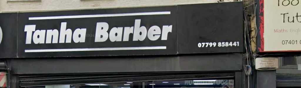 The Tanha Barber shop sign: white lettering and the shop's phone number on a black fascia