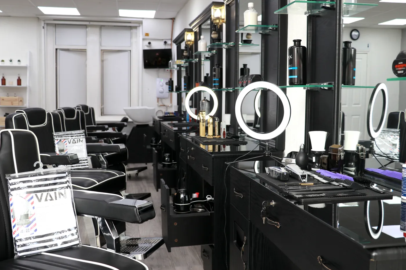 Inside The Modern Barbers — black gloss stations, blue neon lights and a product wall