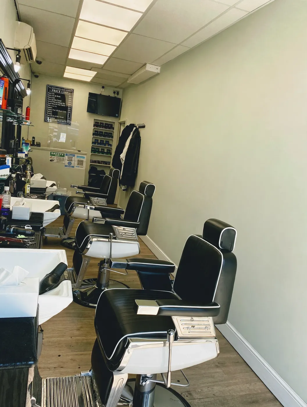 Inside The Shepherd's Bush Barbers — a row of black and chrome barber chairs and the price board