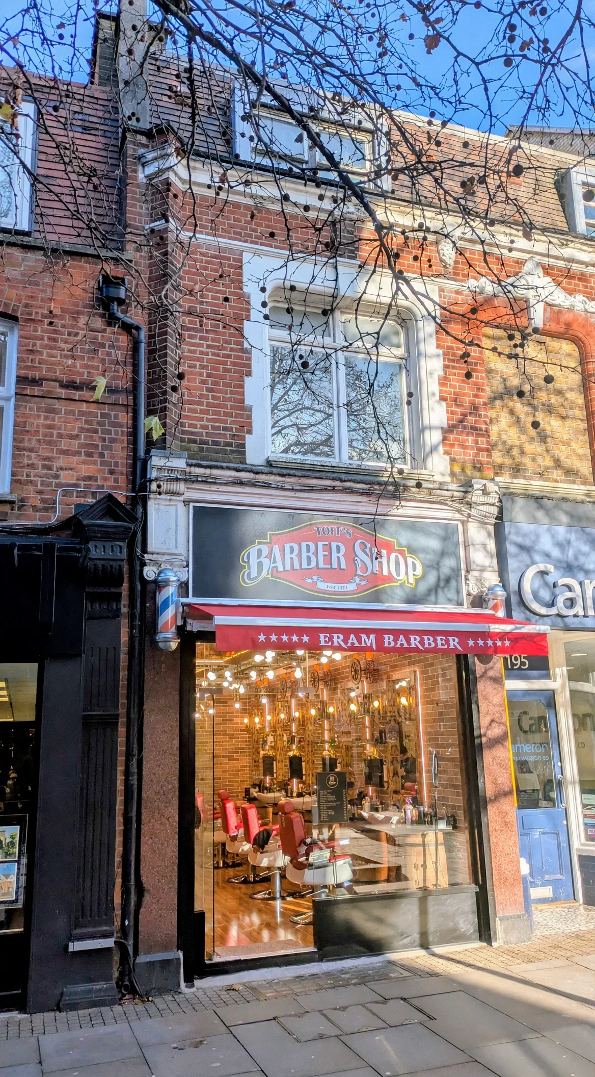 Toff's Barber Shop frontage on Uxbridge High Street: a painted Toff's Barber Shop fascia and red Eram Barber awning over a glowing full-height glass front