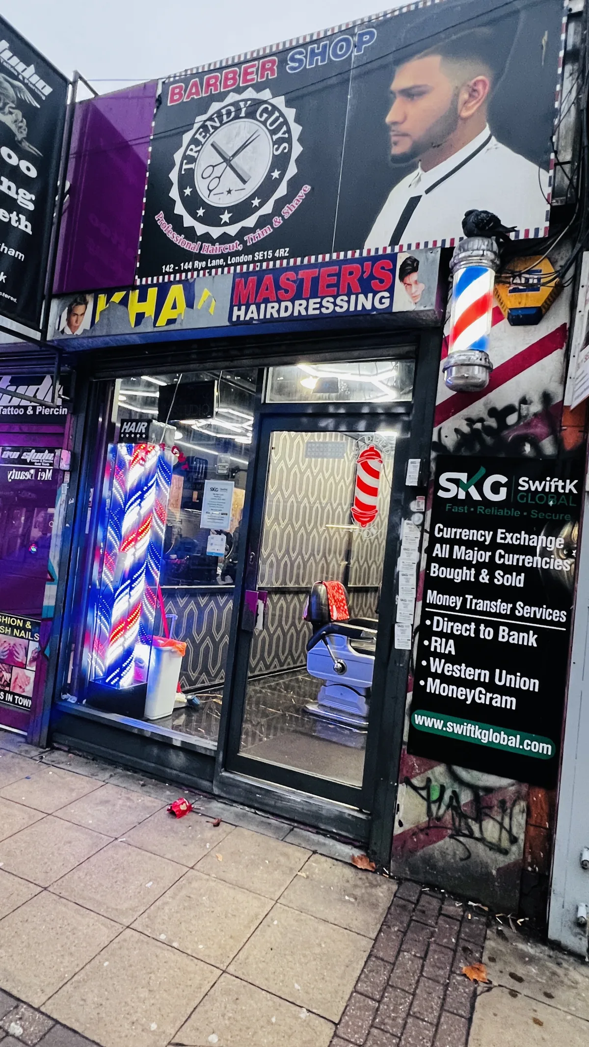 Trendy Guys on Rye Lane: the big Trendy Guys signboard, barber poles and the glass front with an empty chair inside