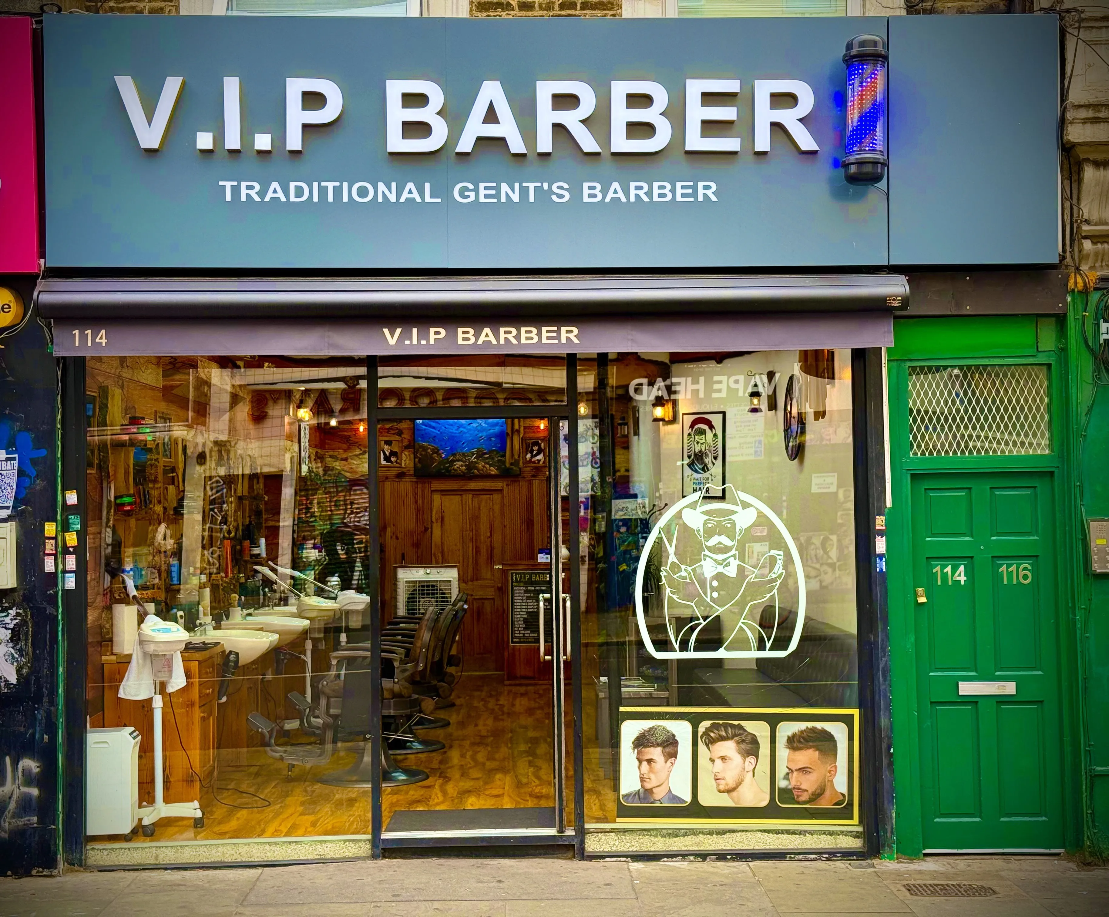 V.I.P Barber on Kingsland High Street: the slate-blue fascia, LED barber pole, awning marked 114 and the green door of 114–116 next door